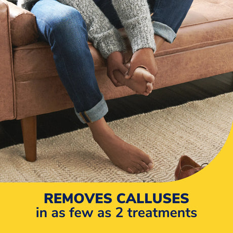 Hands applying callus remover bandage to bare foot