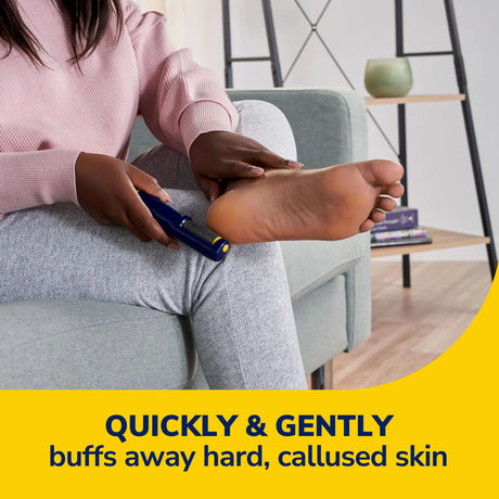Person using an electronic foot file on a foot while seated on a couch