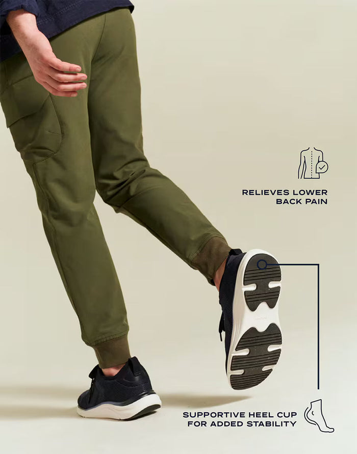 Person wearing green pants and black sneakers with text highlighting shoe features on a beige background