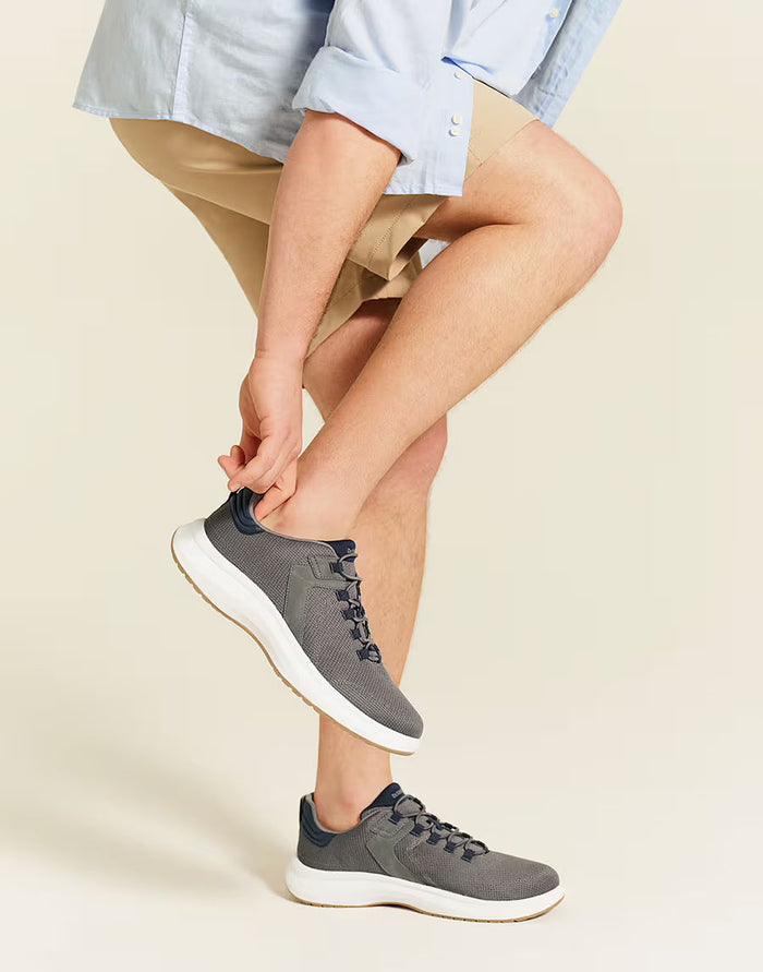 Person wearing gray sneakers on a beige background