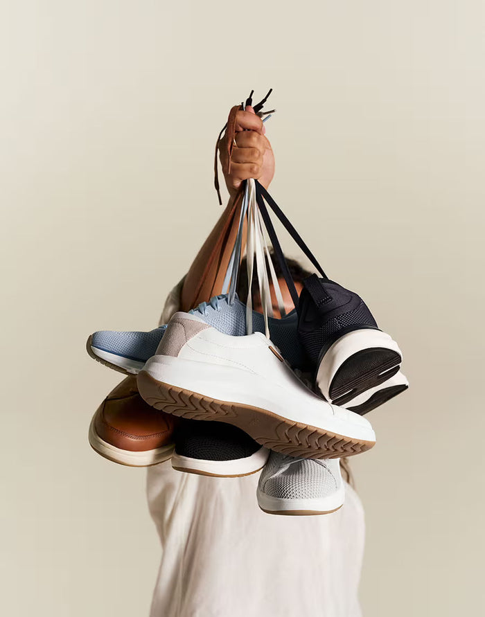 Person holding a pyramid of shoes with a neutral background